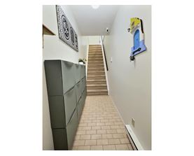 A hallway with a staircase and a wall hanging.