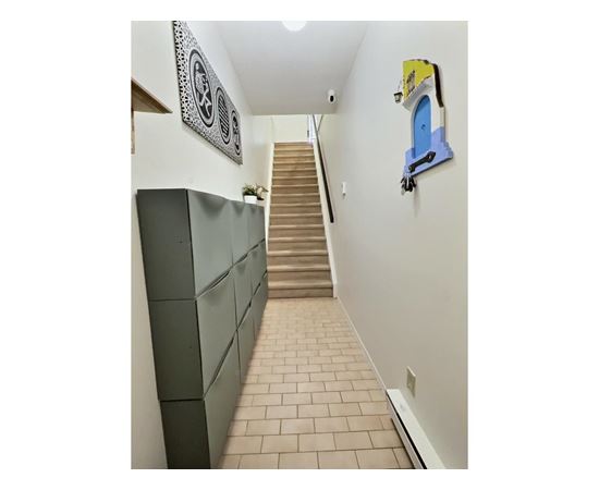 A hallway with a staircase and a wall hanging.