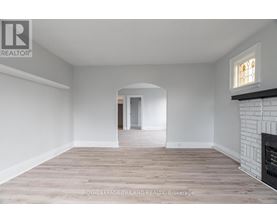 A spacious room with a fireplace and a doorway leading to another room.