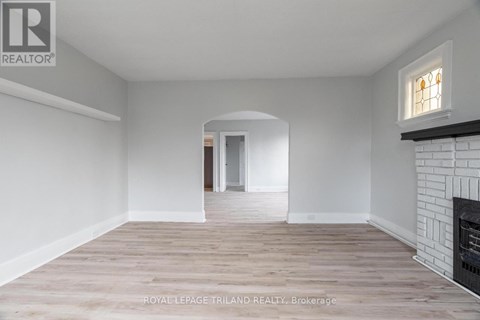 A spacious room with a fireplace and a doorway leading to another room.