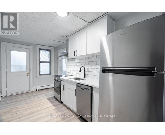 A modern kitchen with a stainless steel refrigerator and white cabinets.