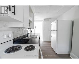 A white kitchen with a stove top oven and a sink.