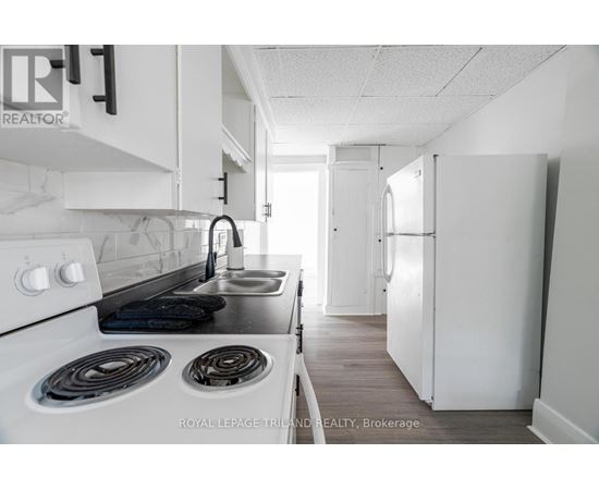 A white kitchen with a stove top oven and a sink.