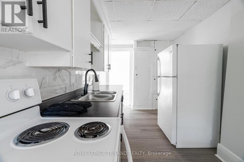 A white kitchen with a stove top oven and a sink.