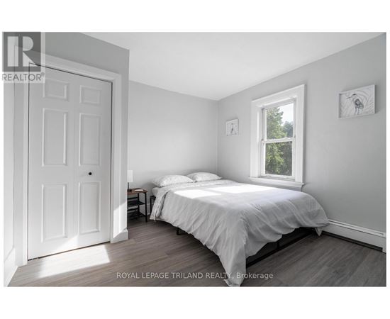 A bedroom with a bed, nightstand, and window.