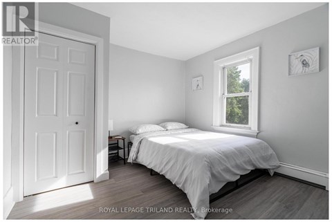 A bedroom with a bed, nightstand, and window.