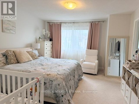A bedroom with a white bed and a white chair.