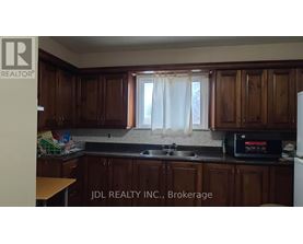 A kitchen with wooden cabinets and a black microwave.
