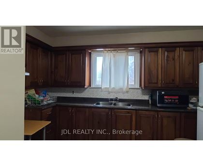 A kitchen with wooden cabinets and a black microwave.