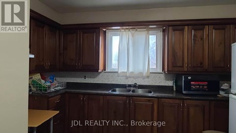 A kitchen with wooden cabinets and a black microwave.