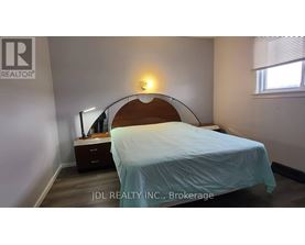 A bedroom with a bed, nightstand, and lamp.