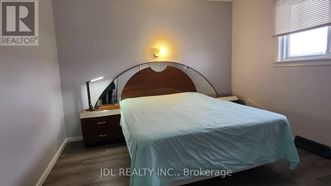 A bedroom with a bed, nightstand, and lamp.