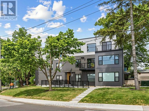 A modern house with a balcony and a tree in front.