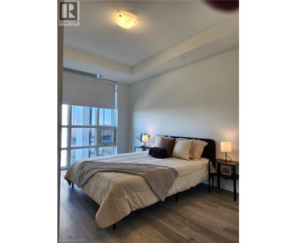 A bedroom with a large bed and a window with blinds.