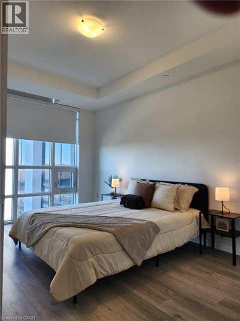 A bedroom with a large bed and a window with blinds.