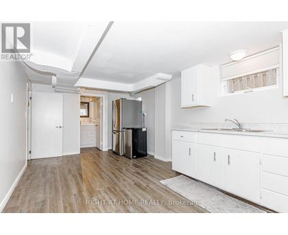 A kitchen with white cabinets and a black fridge.