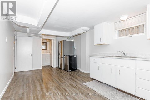 A kitchen with white cabinets and a black fridge.