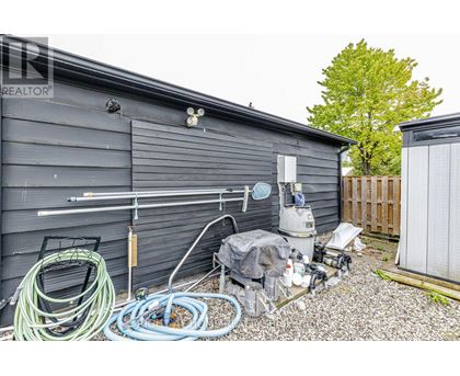 A shed with a pool pump and hoses outside.