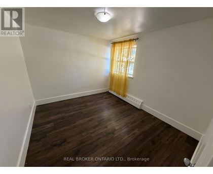 A room with wooden flooring and a window with yellow curtains.