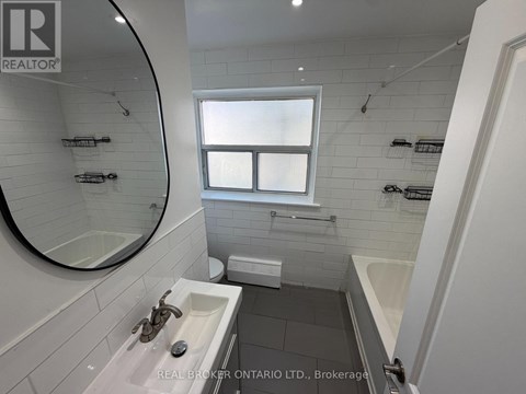 A bathroom with a sink, mirror, and bathtub.