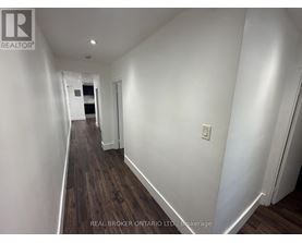 A long hallway with wood floors and white walls.