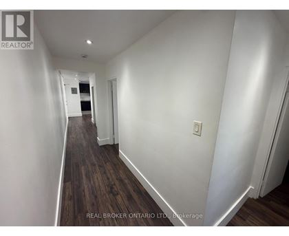 A long hallway with wood floors and white walls.