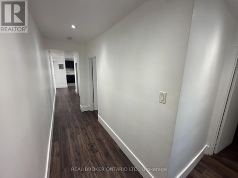 A long hallway with wood floors and white walls.