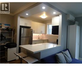 A kitchen with a refrigerator, sink, and cabinets.