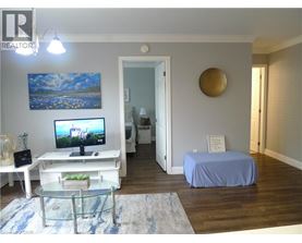 A bedroom with a bed covered in a blue sheet, a television, and a painting on the wall.