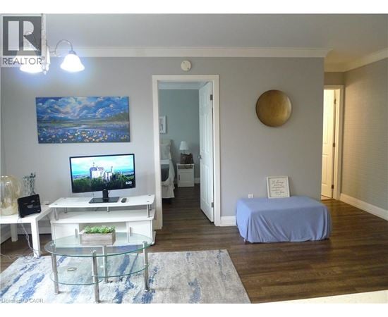 A bedroom with a bed covered in a blue sheet, a television, and a painting on the wall.