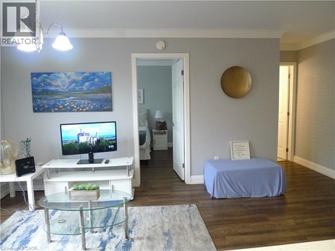 A bedroom with a bed covered in a blue sheet, a television, and a painting on the wall.