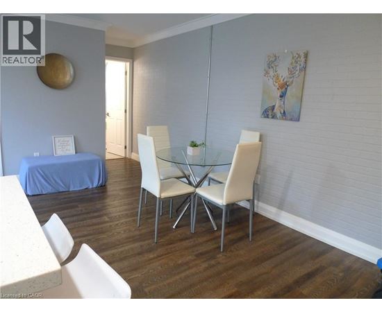 A dining room with a glass table and white chairs.