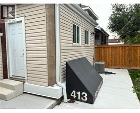 A black mailbox with the number 413 on it is in front of a house.