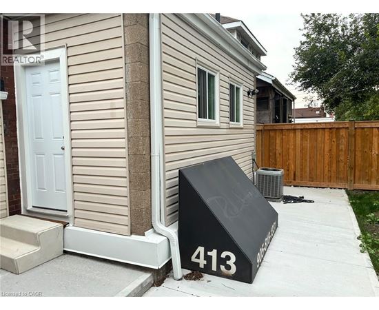 A black mailbox with the number 413 on it is in front of a house.