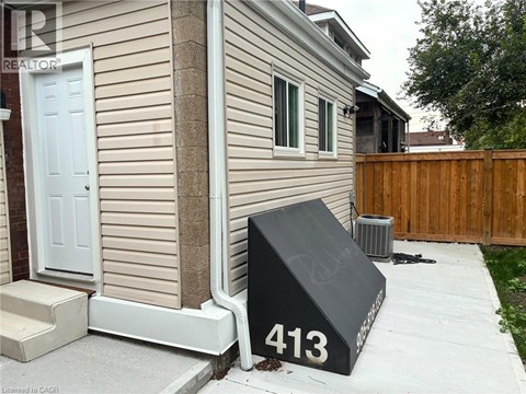 A black mailbox with the number 413 on it is in front of a house.