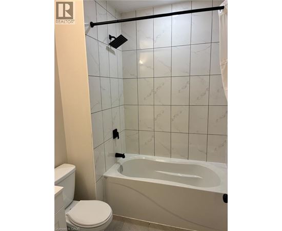A white bathroom with a toilet, tub, and tiled walls.