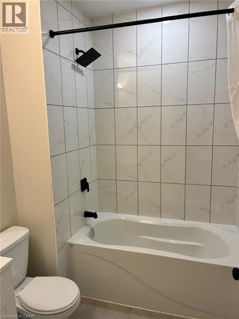A white bathroom with a toilet, tub, and tiled walls.