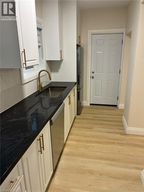 A kitchen with white cabinets and a black counter top.