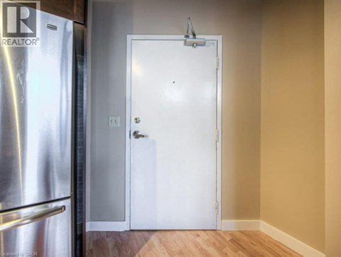 A white door is in a room with a refrigerator on the left.