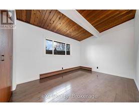 A room with wooden floors and a window with a view of trees outside.