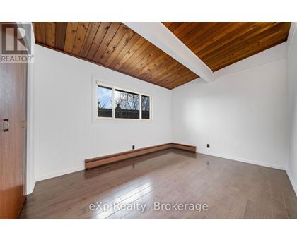 A room with wooden floors and a window with a view of trees outside.