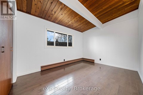 A room with wooden floors and a window with a view of trees outside.