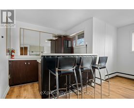 A dining area with a wooden floor, white walls, and a mirrored cabinet.