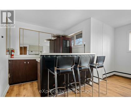 A dining area with a wooden floor, white walls, and a mirrored cabinet.