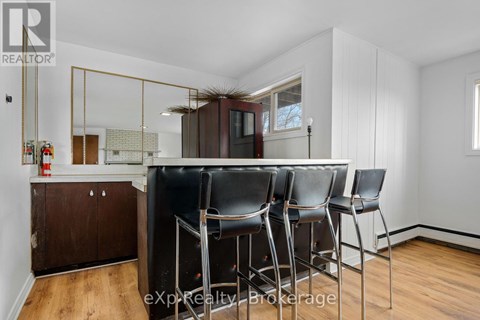 A dining area with a wooden floor, white walls, and a mirrored cabinet.
