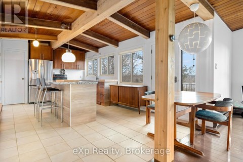 A kitchen with a wooden ceiling and a dining table with chairs.