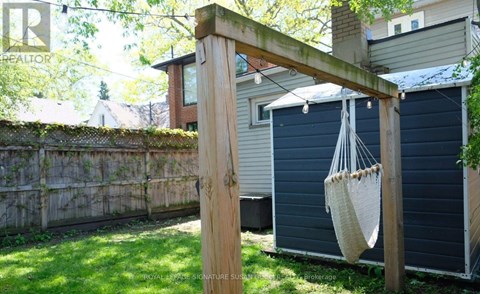 A wooden pergola with a hanging planter is in the foreground of a backyard.