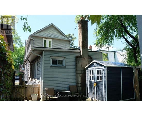 A house with a grey exterior and a small shed in front.