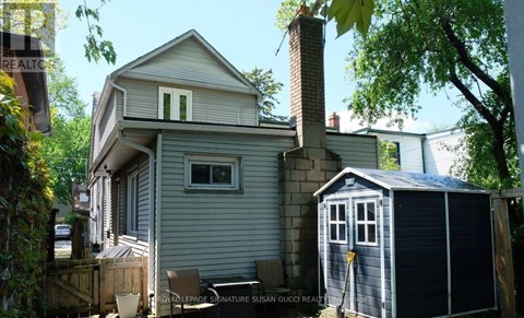 A house with a grey exterior and a small shed in front.