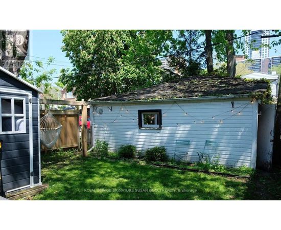 A small white shed with a window and a door is surrounded by a green lawn.